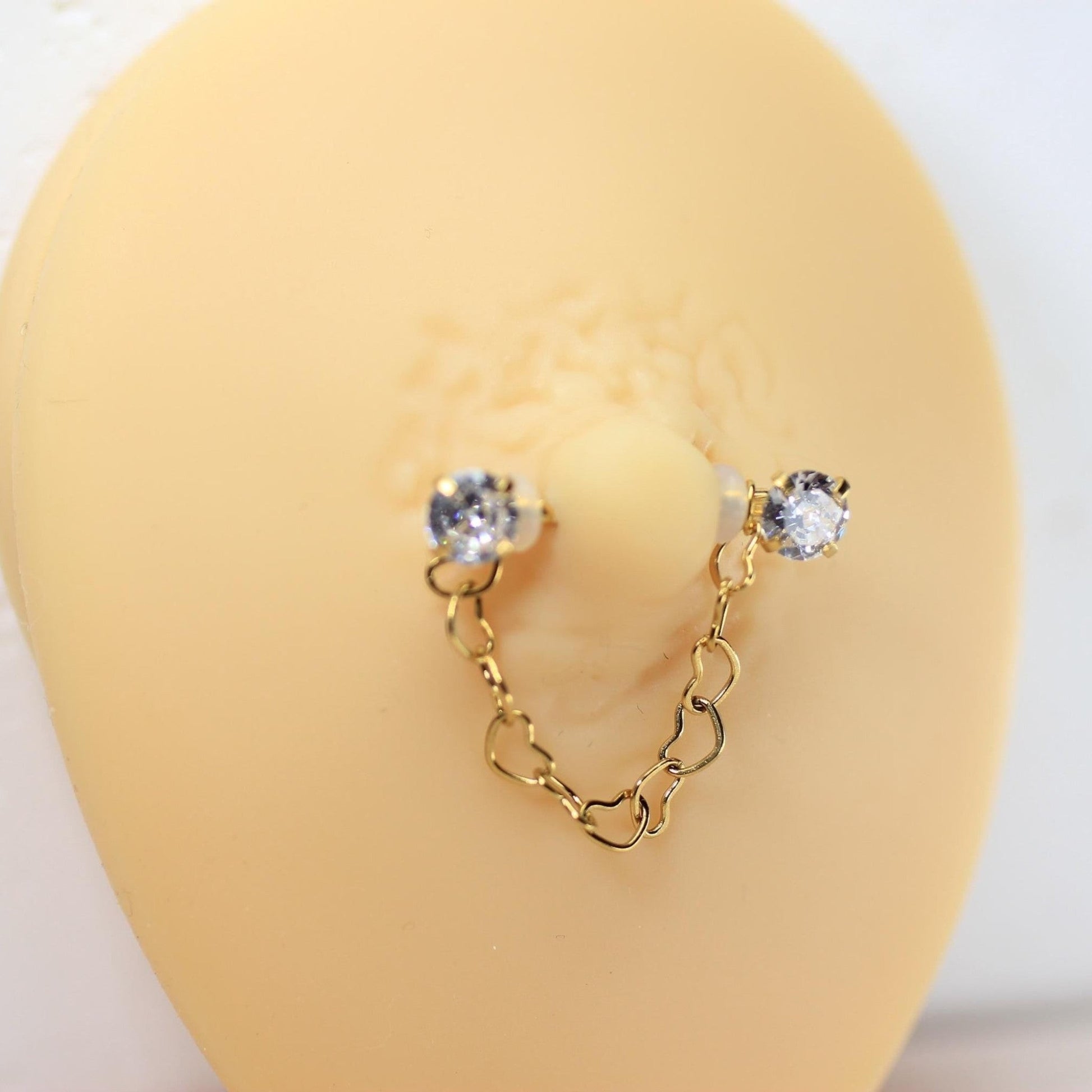 MKBodyJewelry gold 14g surgical steel nipple barbell with dangling heart chain and CZ prong ends.