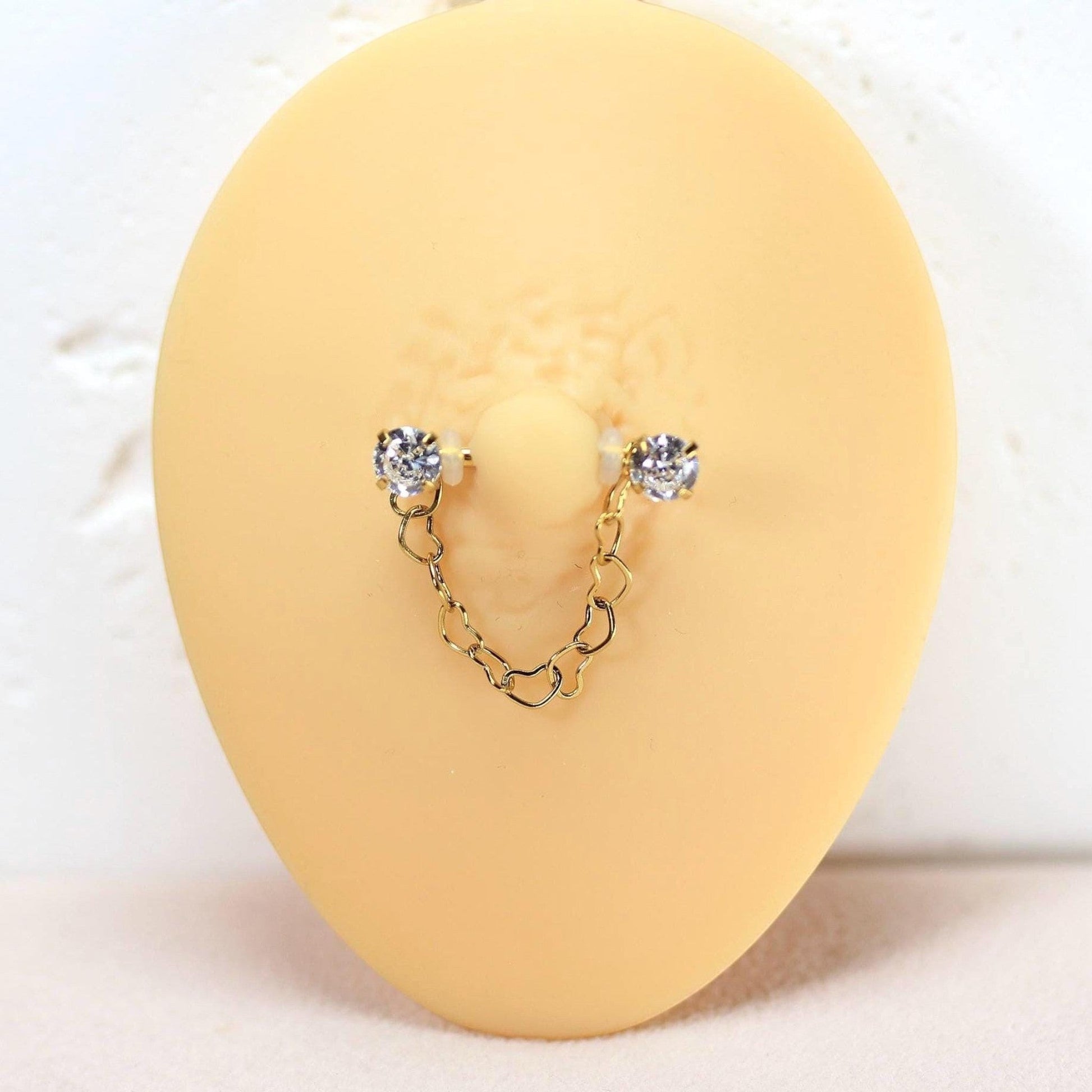 MKBodyJewelry 14g gold surgical steel nipple barbell with dangling heart chain and CZ prong ends.