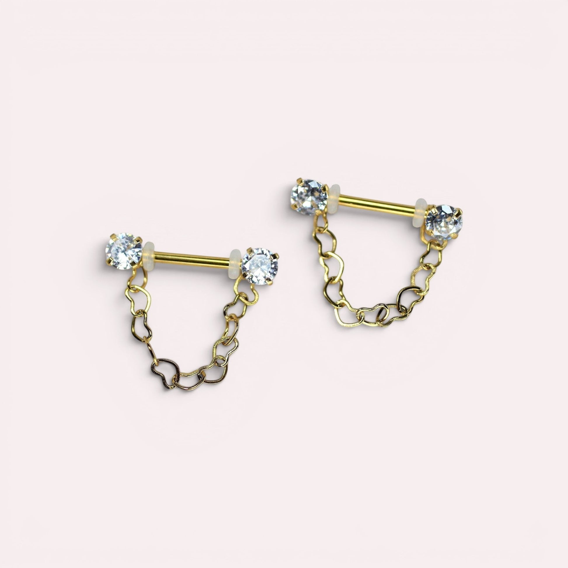 MKBodyJewelry gold surgical steel nipple barbell with dangling heart chain and CZ prong ends. Sold as a pair.