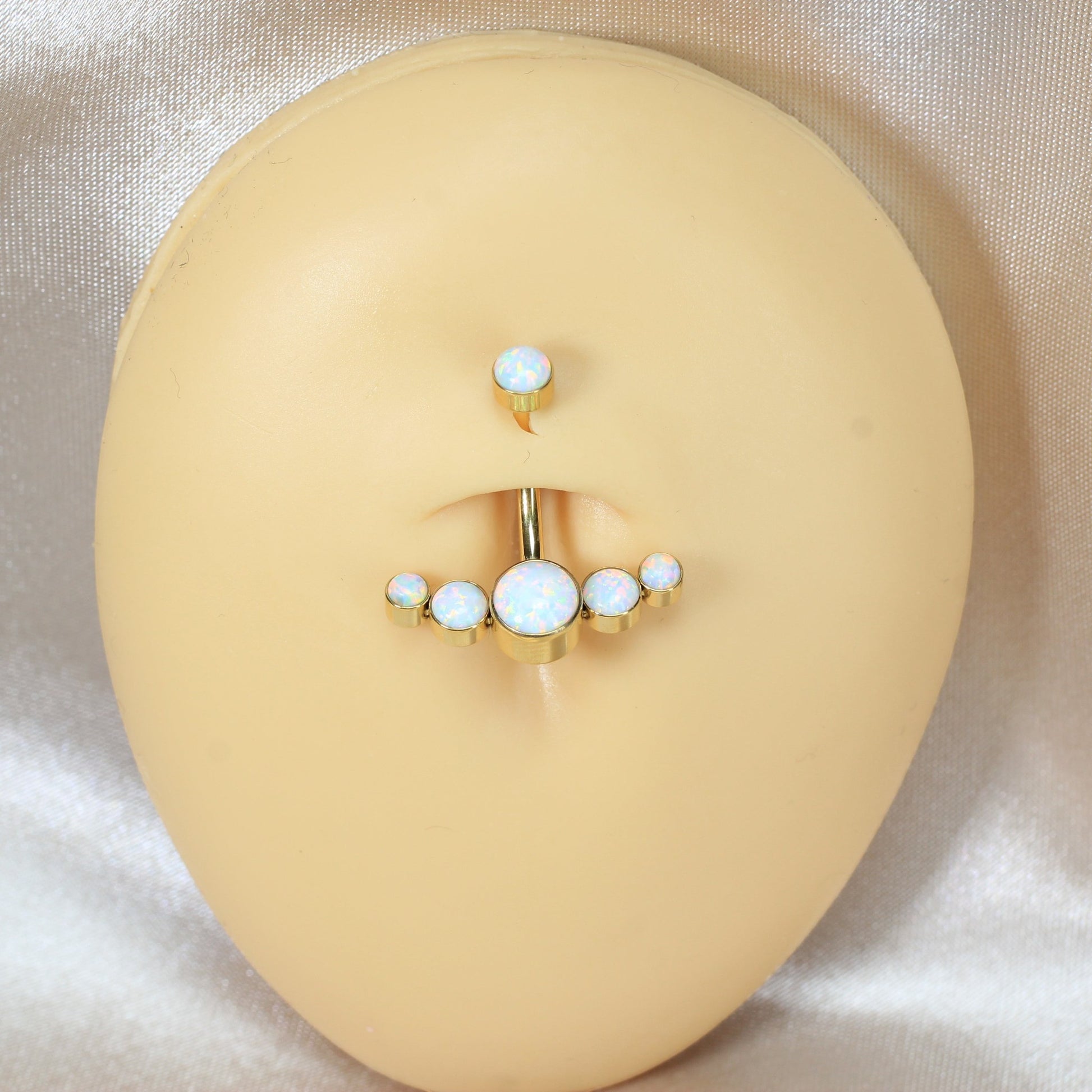 MKBodyJewelry 14G gold titanium floating navel ring featuring a curved bar with five white opal stones on a display.