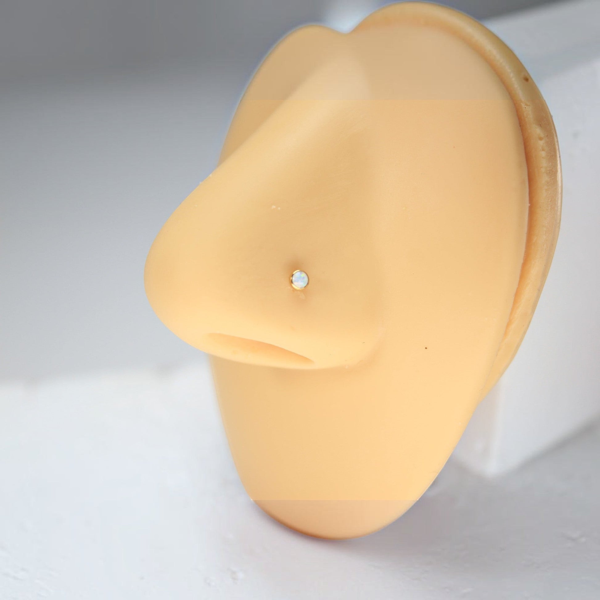 MKBodyJewelry gold titanium nose stud with a round opal gem on a mannequin nose model