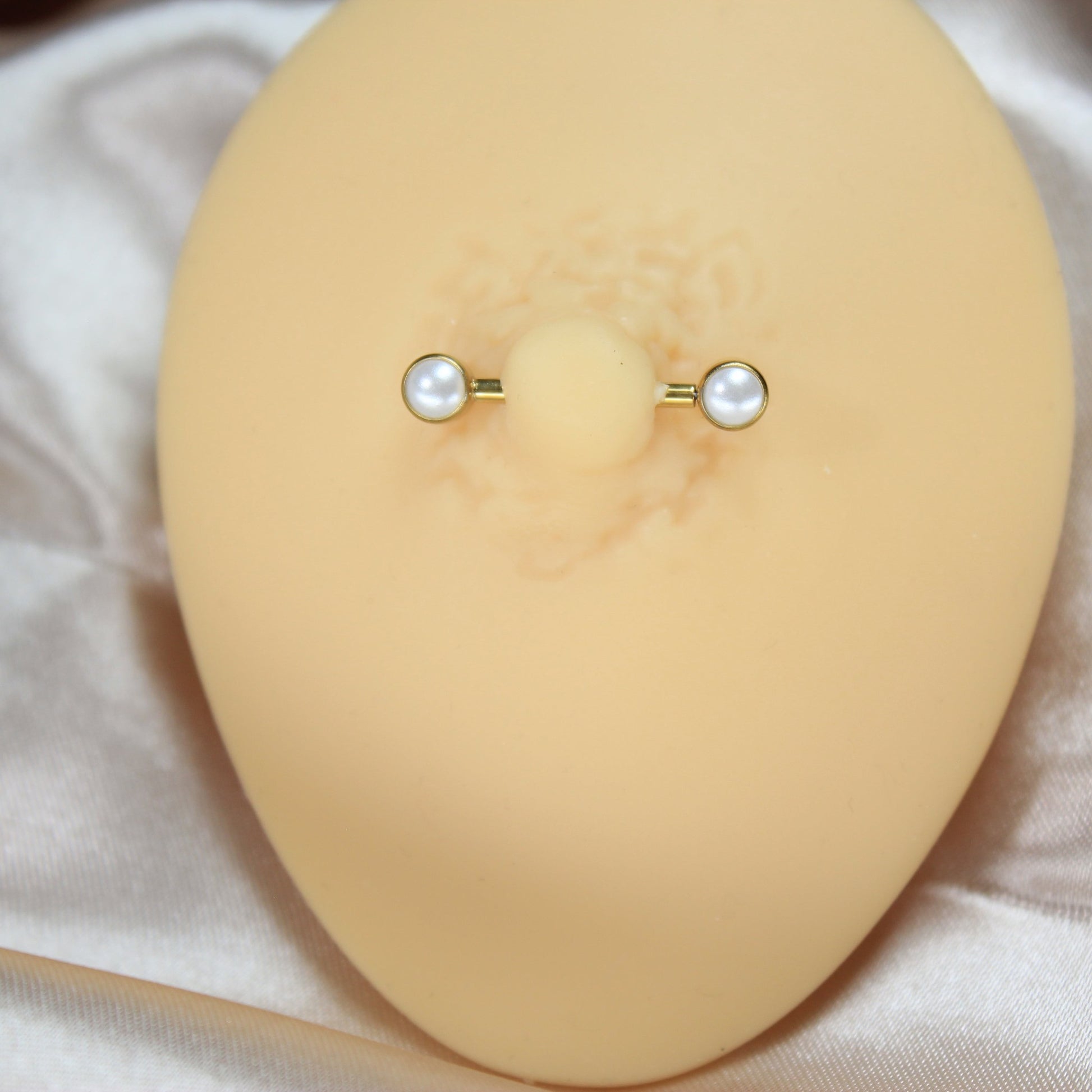 MKBodyJewelry 14g gold titanium threadless nipple barbell with 5mm pearl ends on a display model
