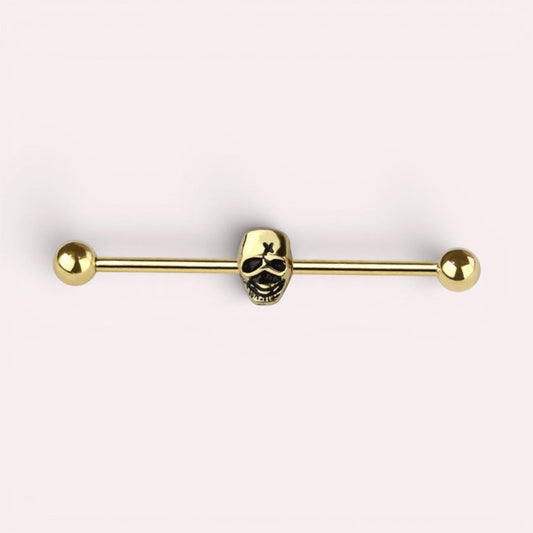 MKBodyJewelry gold industrial barbell featuring a detailed skull charm for cartilage piercings.