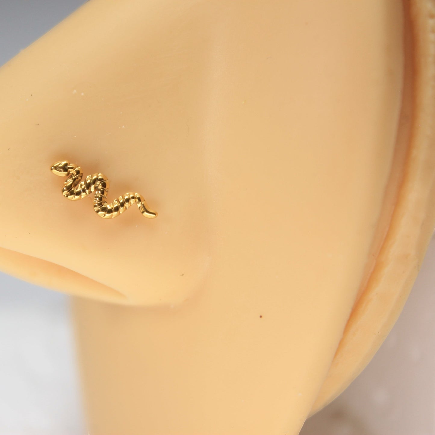MKBodyJewelry gold snake nose stud in surgical steel with an L-bend post worn on a mannequin nose