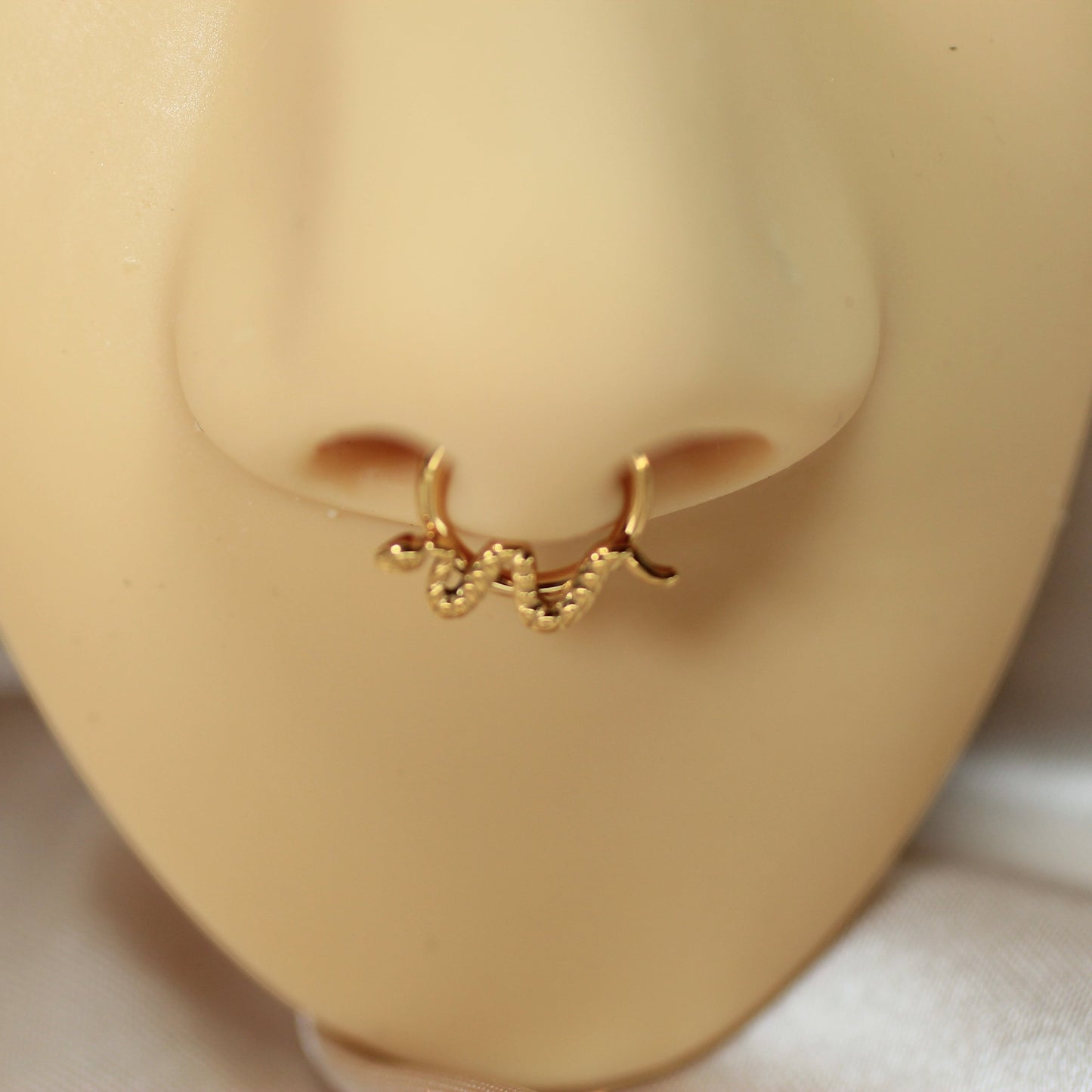 MKBodyJewelry 16g gold snake septum clicker ring made of hypoallergenic implant grade titanium on a nose model