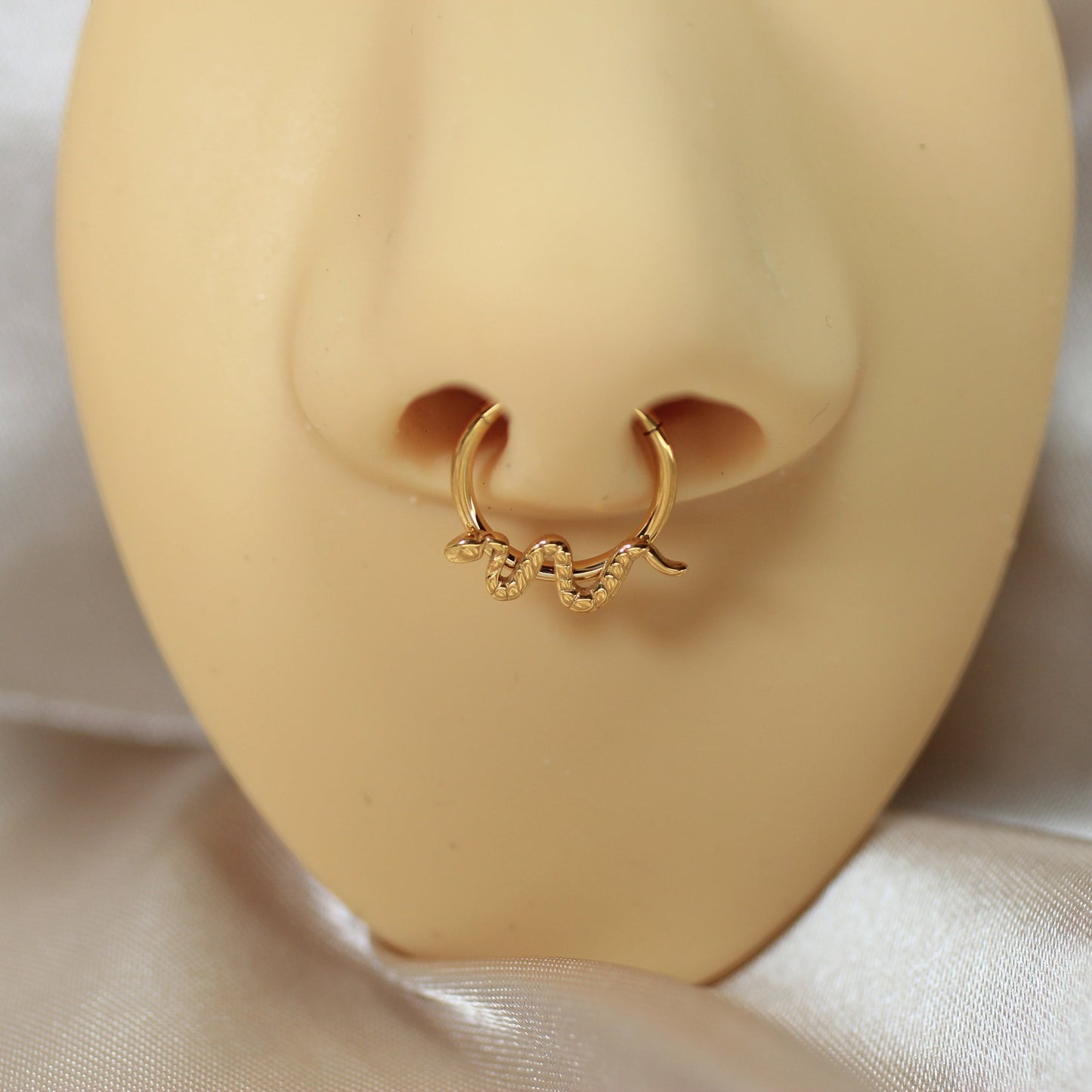 MKBodyJewelry gold titanium snake septum clicker ring on a mannequin nose, featuring a minimalist hinged hoop design.