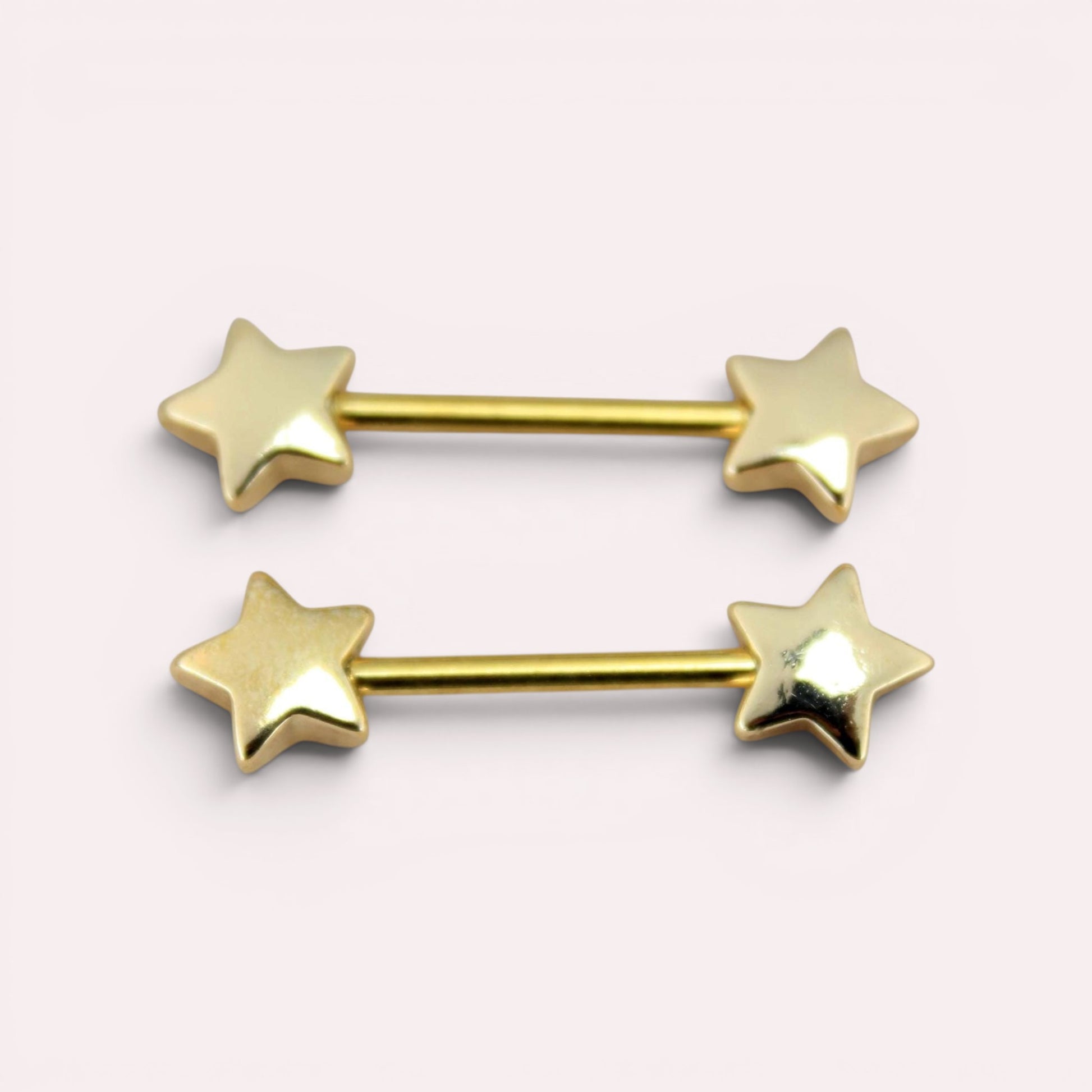 MKBodyJewelry pair of 14G gold-tone surgical steel nipple barbells with minimalist star ends on a light background.