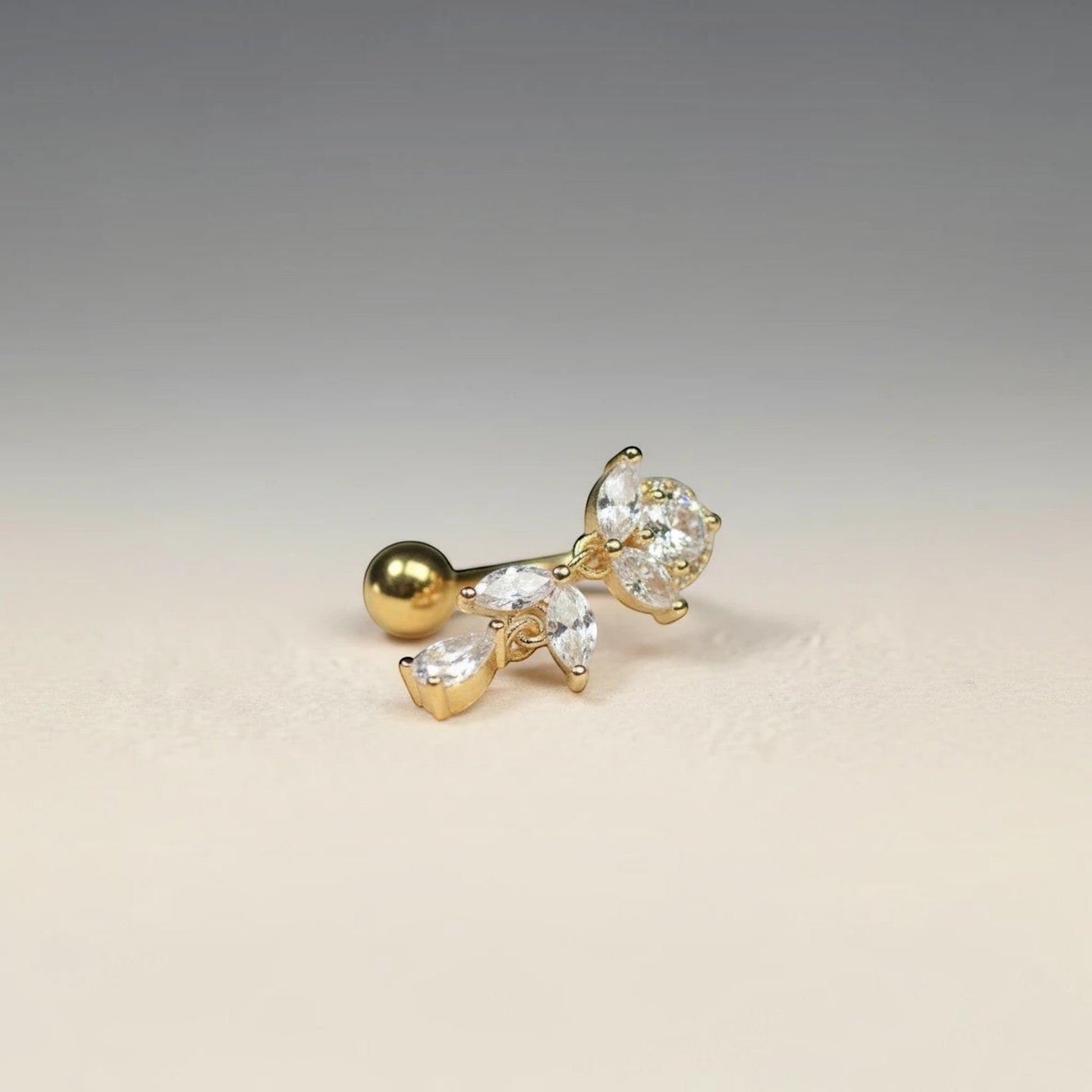 MKBodyJewelry gold titanium inverted floral belly button ring with CZ stones and a dangling charm.