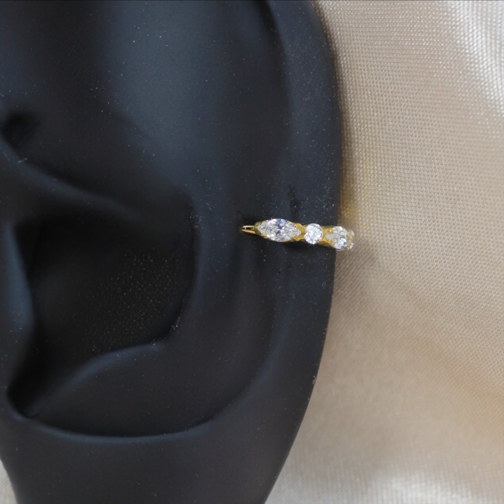 MKBodyJewelry gold titanium hinged nose clicker ring with sparkling CZ gems on a black ear display model