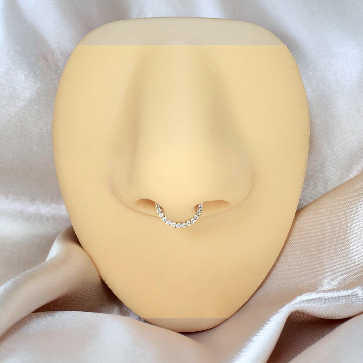 MKBodyJewelry 16G gold titanium septum clicker ring with a dainty gem line on a mannequin nose display.