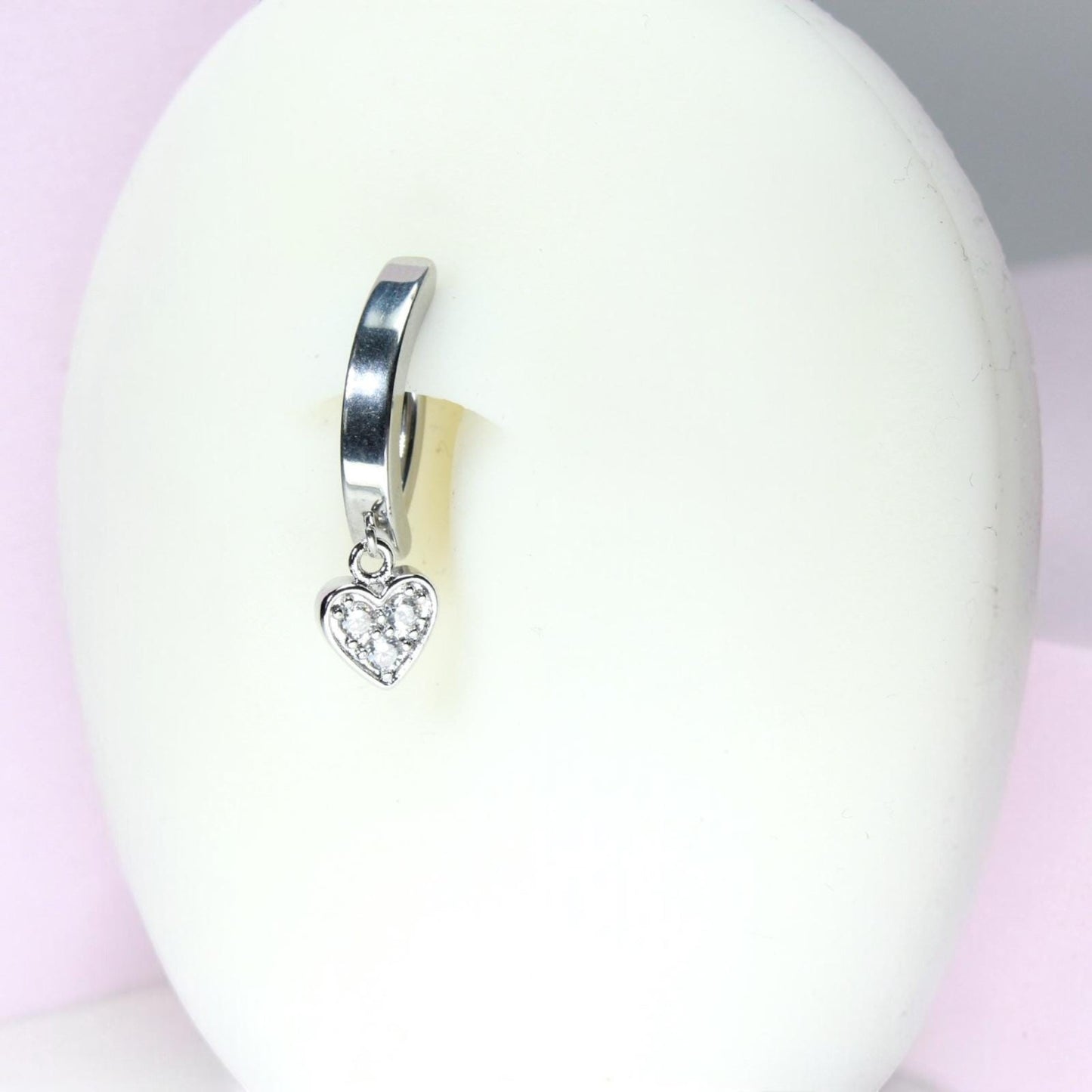 MKBodyJewelry silver surgical steel belly button ring with a dangling heart charm featuring dainty crystals.