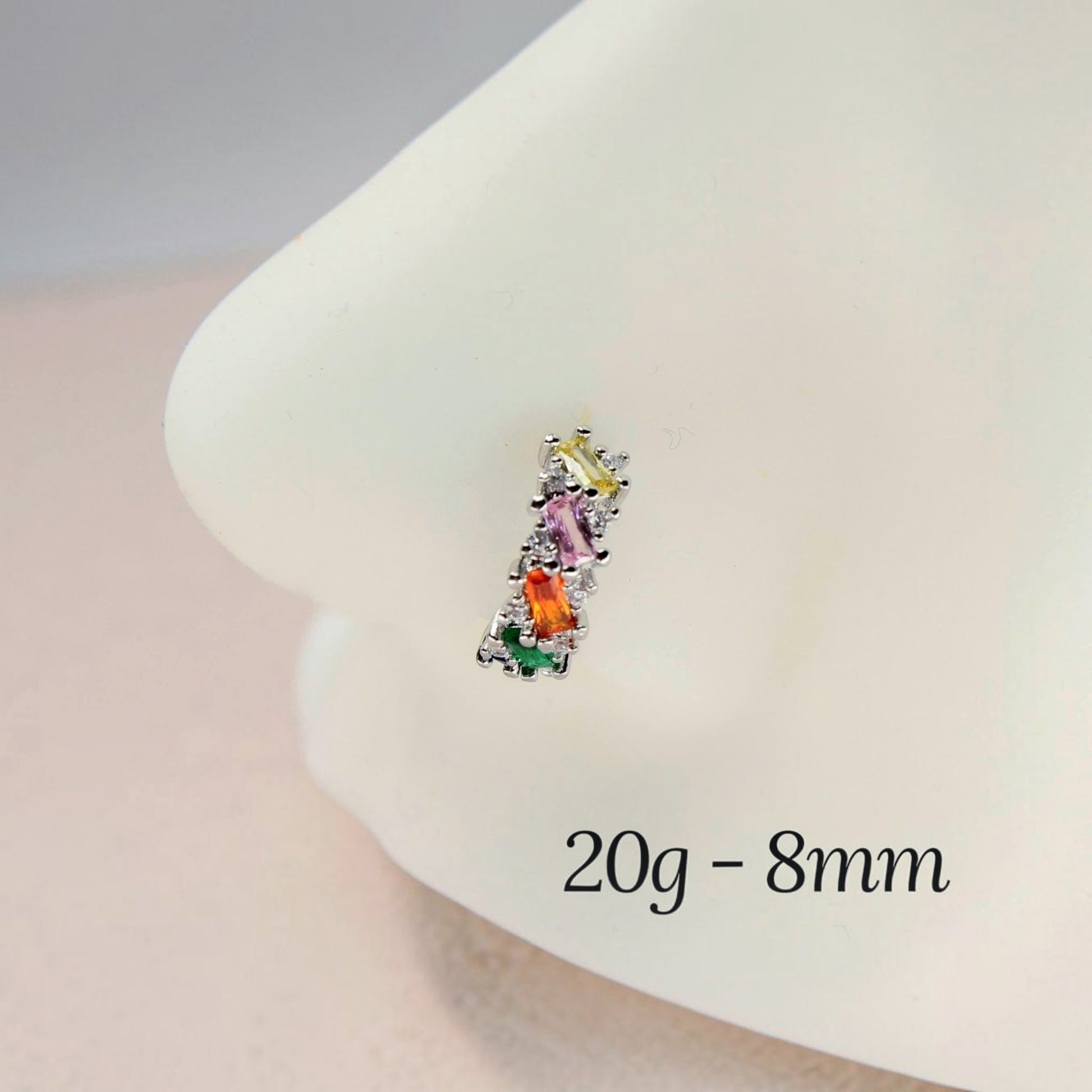 MKBodyJewelry 20g silver nose hoop with multicolor baguette cubic zirconia stones on a white display model