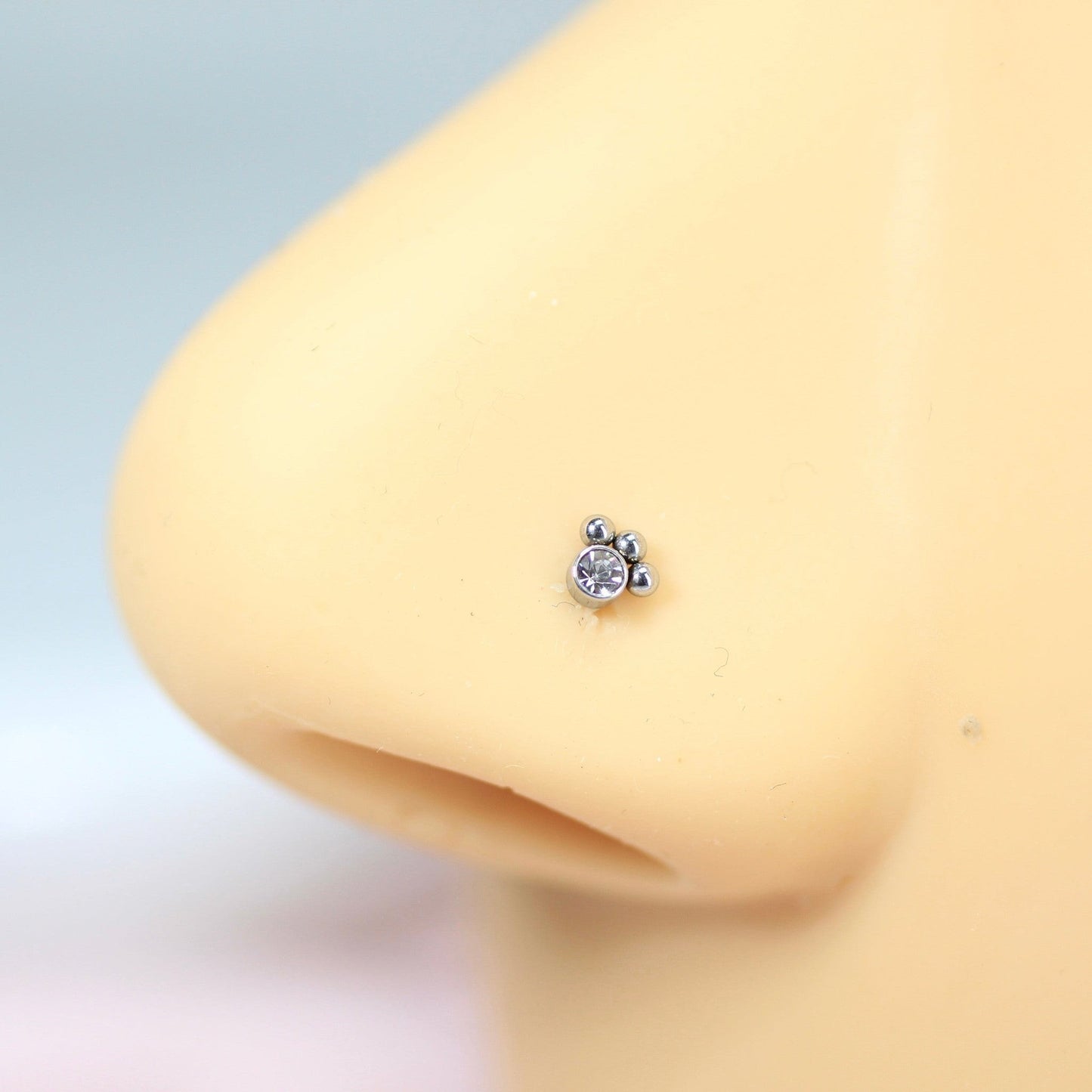 MKBodyJewelry 20G stainless steel paw print nose stud with a clear crystal accent on a mannequin nose