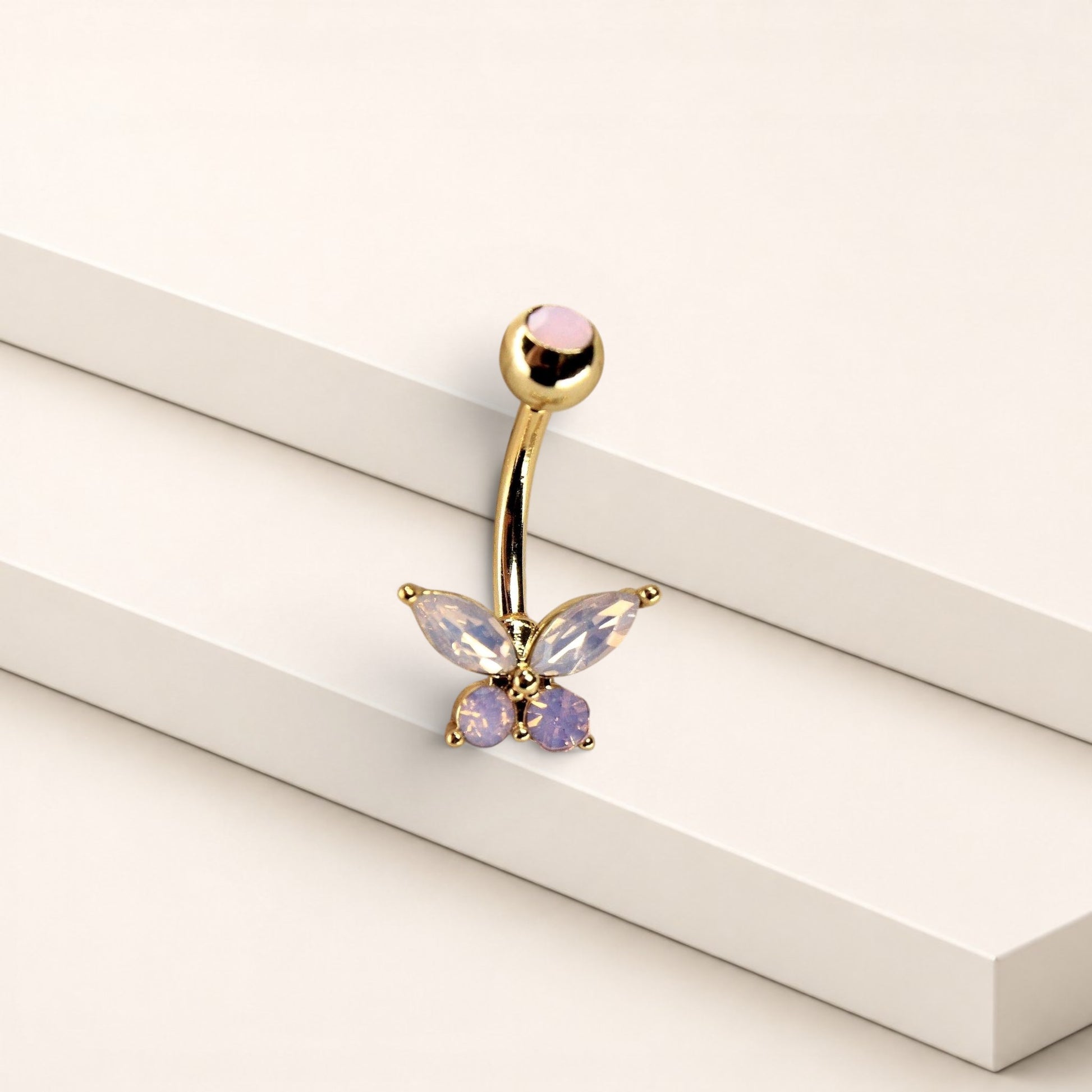 MKBodyJewelry pink butterfly belly ring in surgical steel with sparkling CZ stones on a minimalist white display