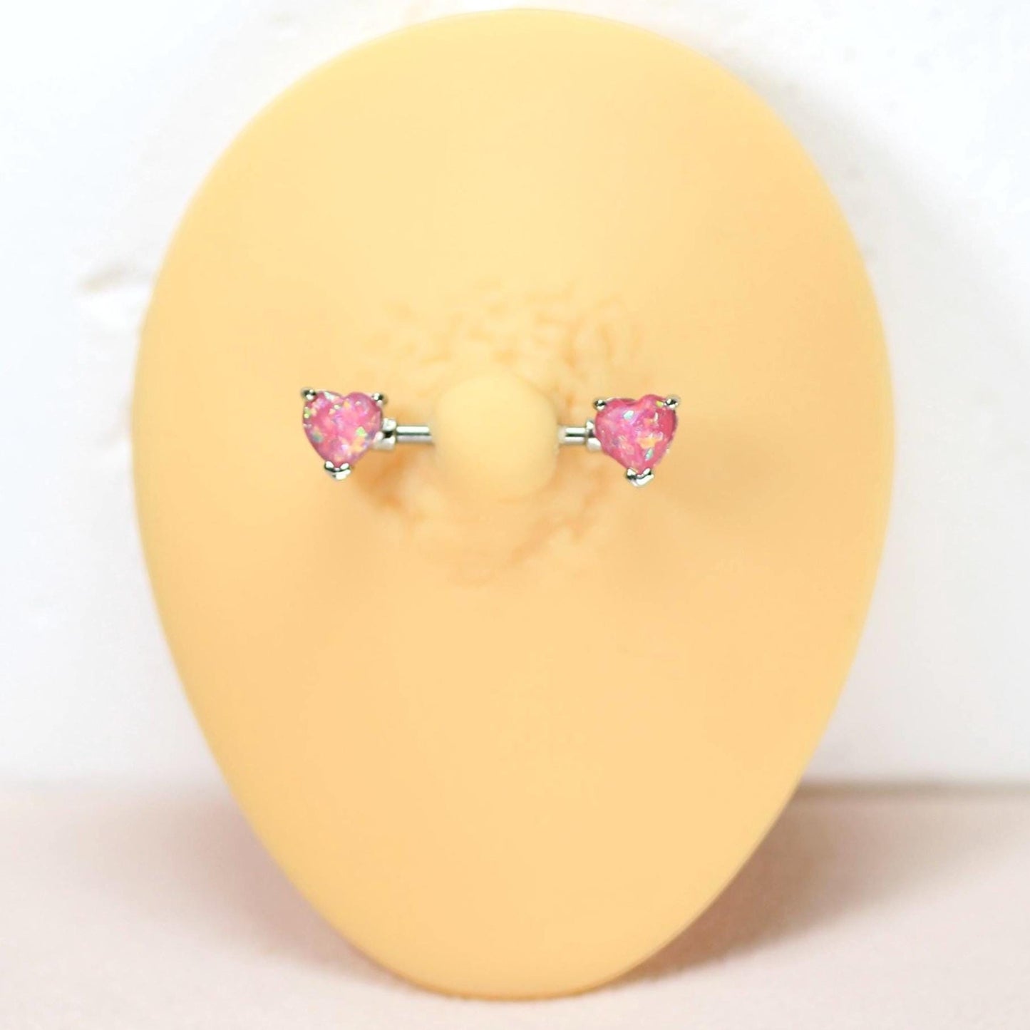MKBodyJewelry 14g surgical steel nipple barbell pair with pink opal heart ends on a display form