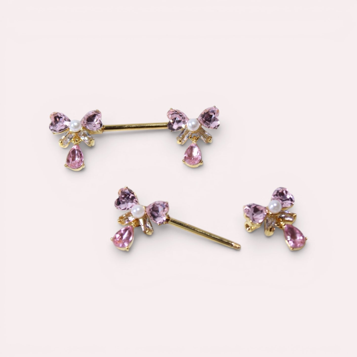 MKBodyJewelry dainty pink ribbon bow nipple rings with teardrop gems and pearl accents. Surgical steel.