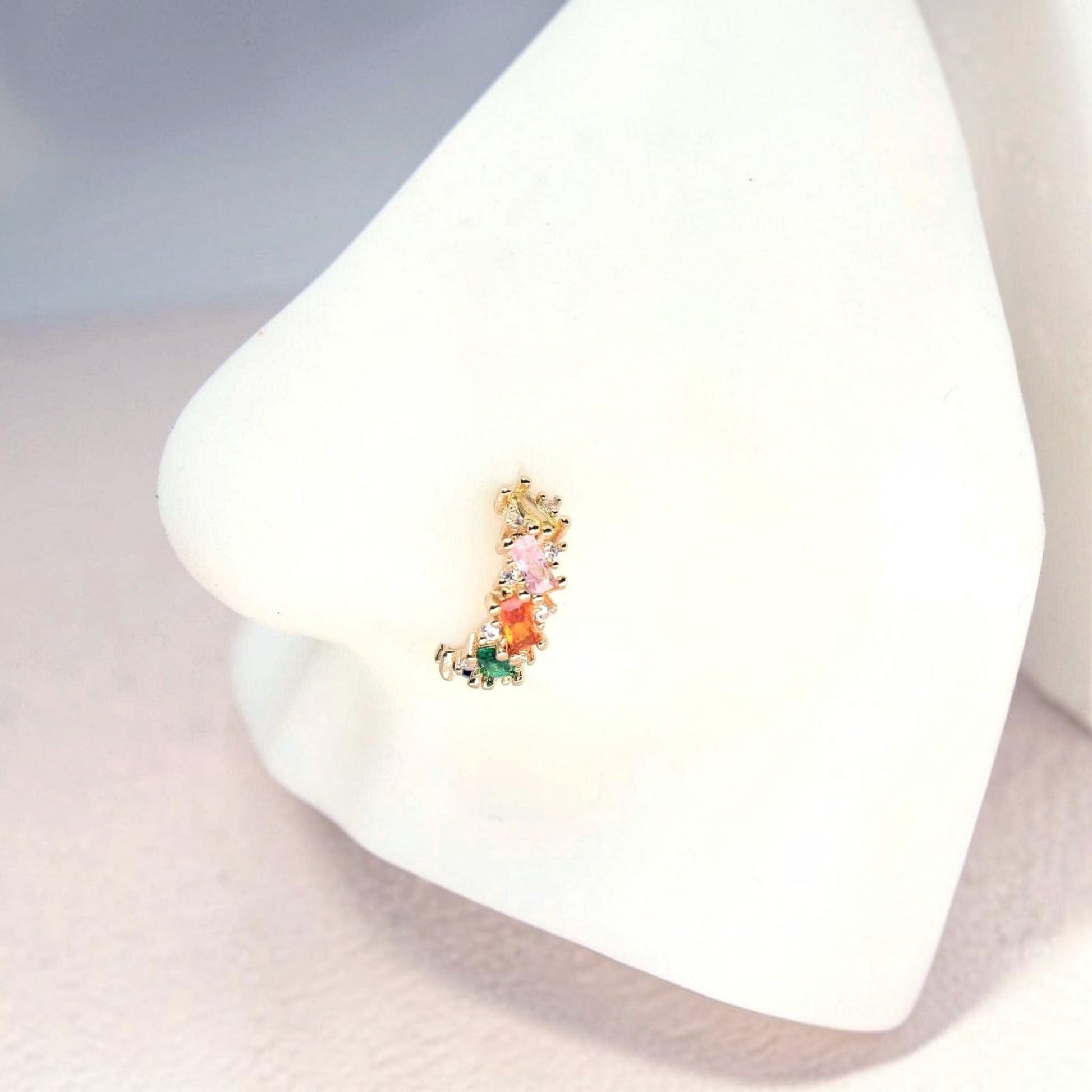 MKBodyJewelry 20g gold nose hoop with rainbow baguette cubic zirconia stones on a white mannequin nose display.