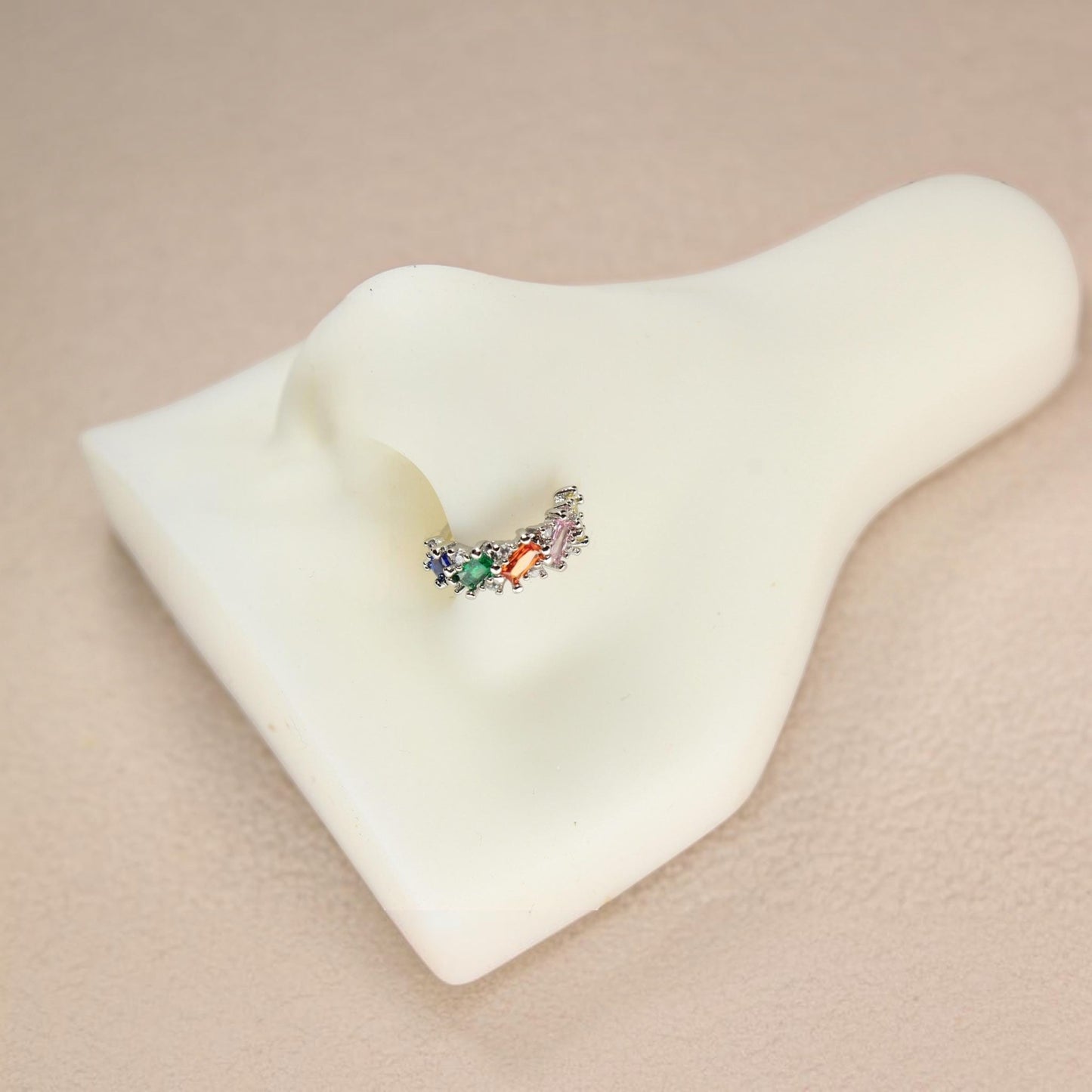 MKBodyJewelry gold nose hoop with rainbow baguette cubic zirconia stones on a white nose display model.