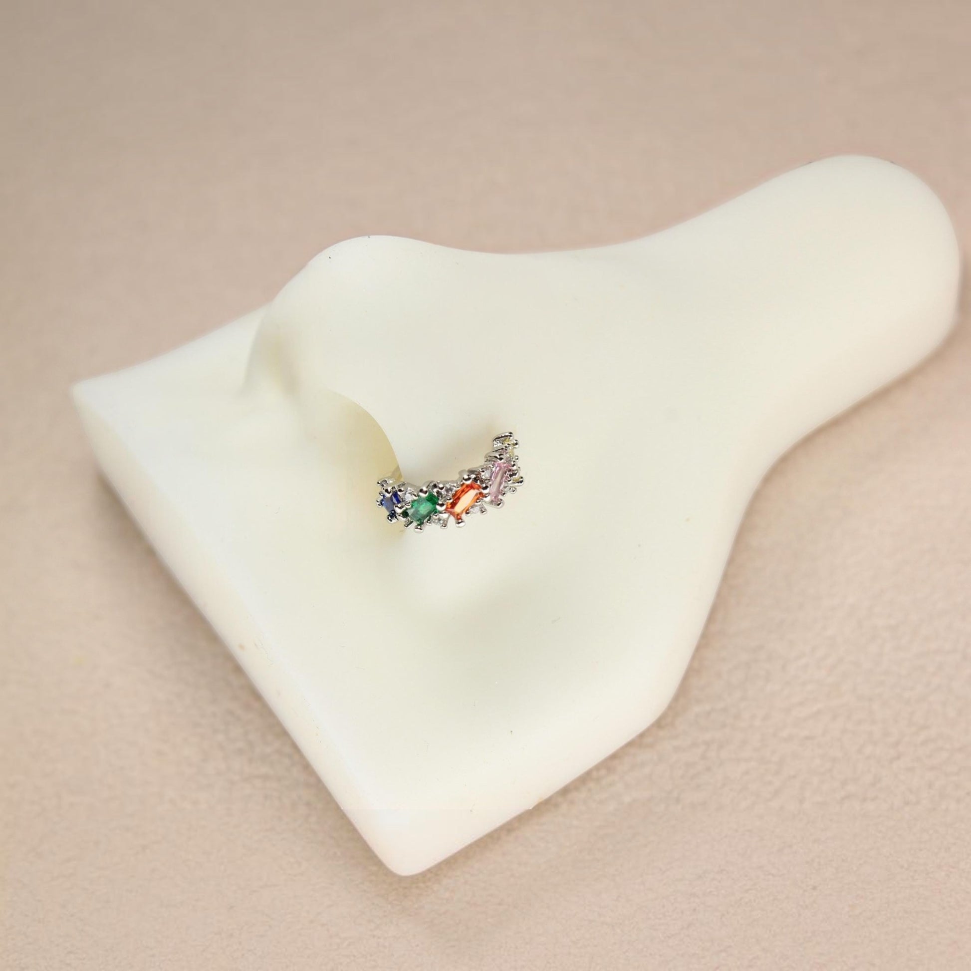 MKBodyJewelry gold nose hoop with rainbow baguette cubic zirconia stones on a white nose display model.