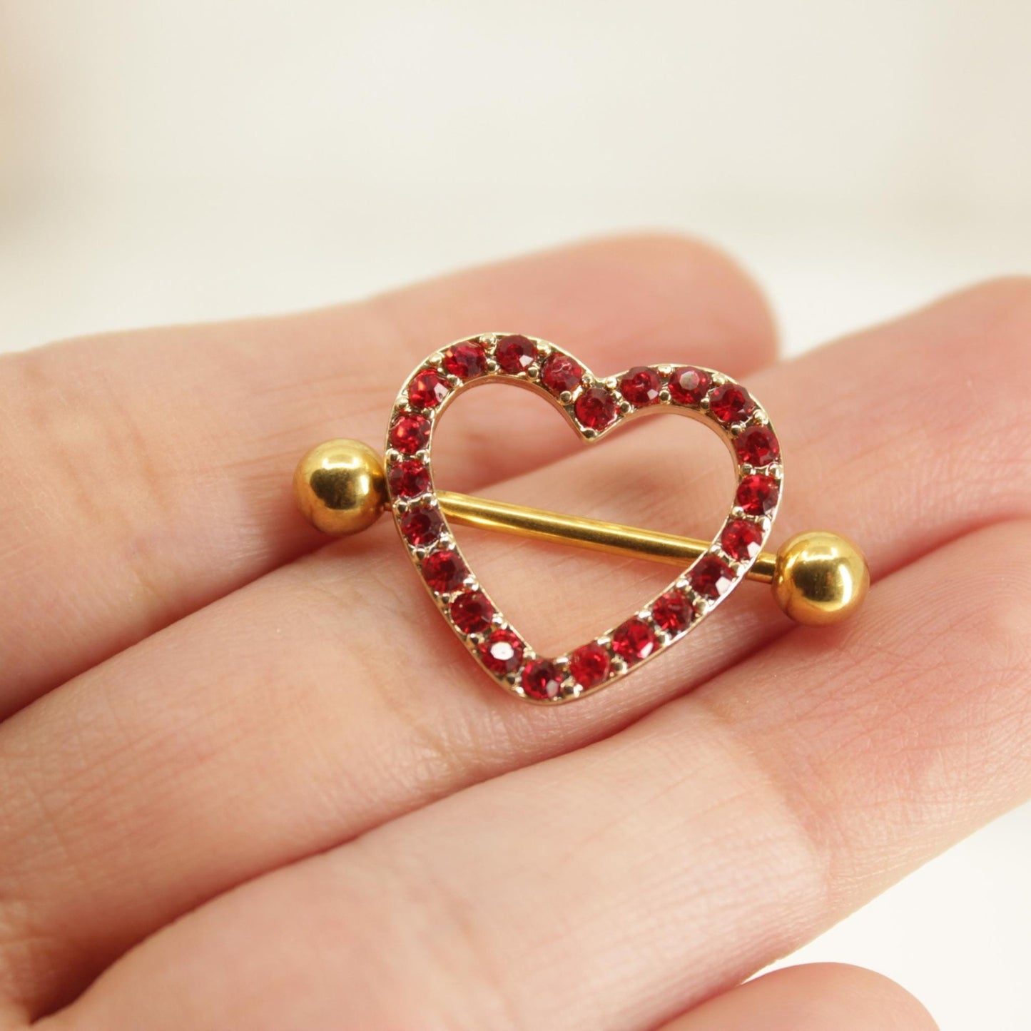 MKBodyJewelry 14g gold surgical steel nipple barbell with a red heart-shaped shield paved with sparkling red gems.