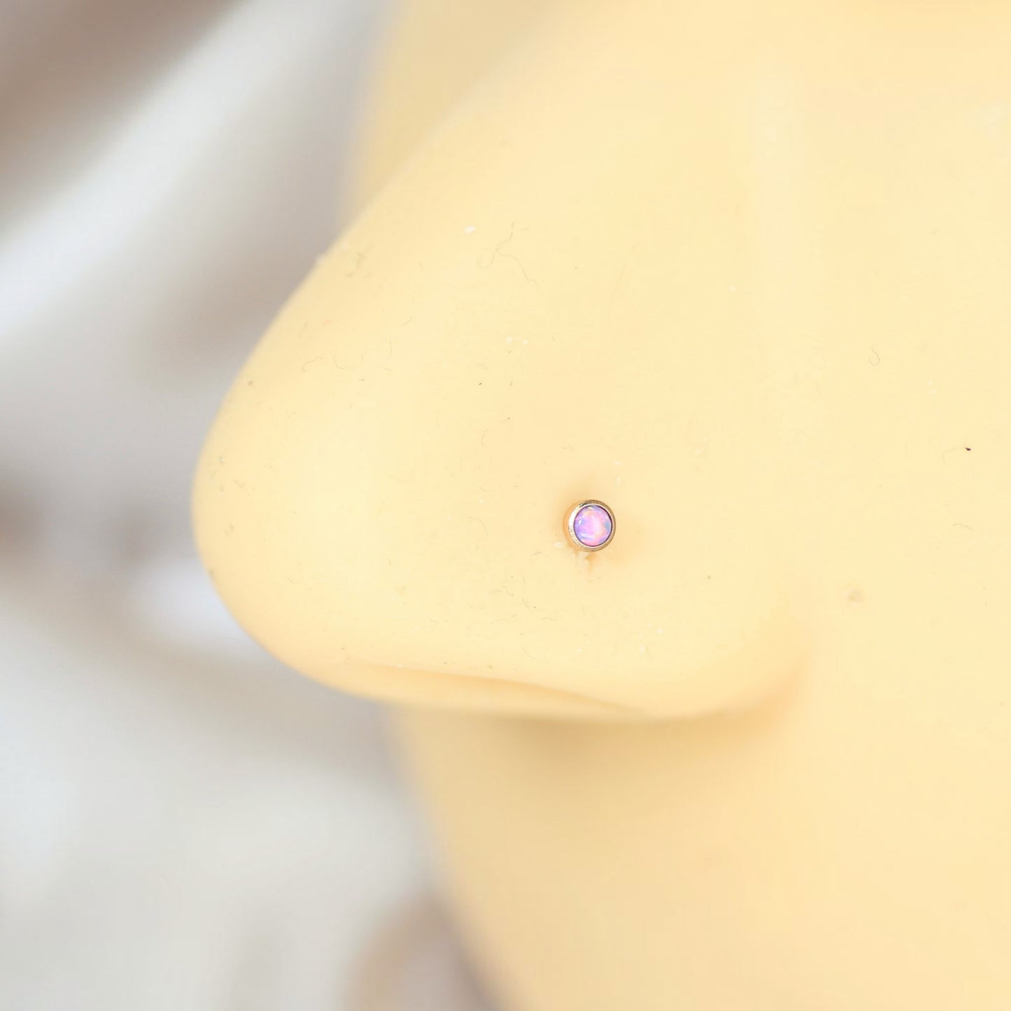 MKBodyJewelry rose gold titanium nose stud with a 2.5mm round opal gem on a mannequin nose