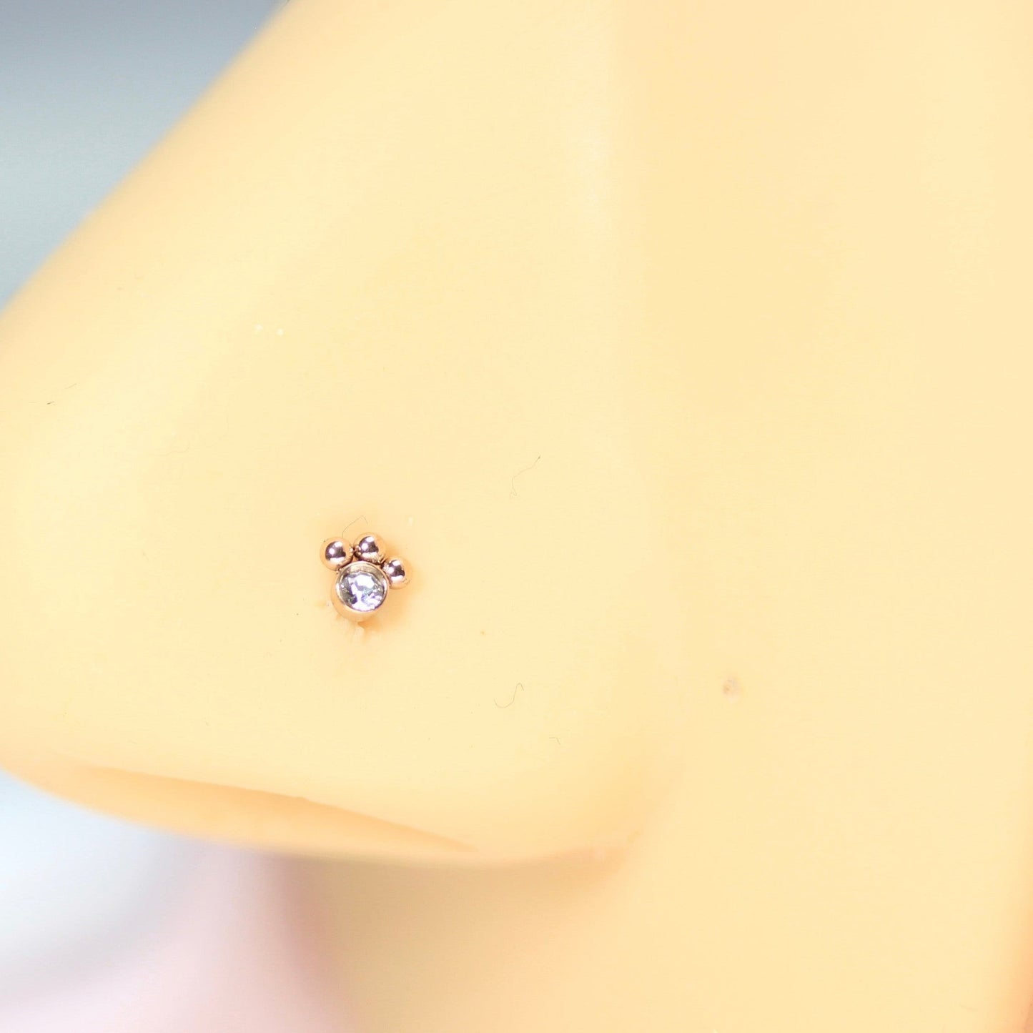MKBodyJewelry 20G rose gold stainless steel paw print nose stud with L-shape post on a mannequin nose