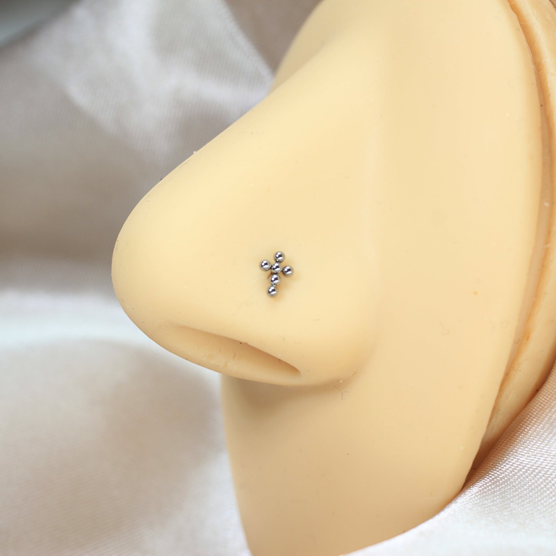 MKBodyJewelry silver beaded cross nose stud made of implant grade titanium on a mannequin nose