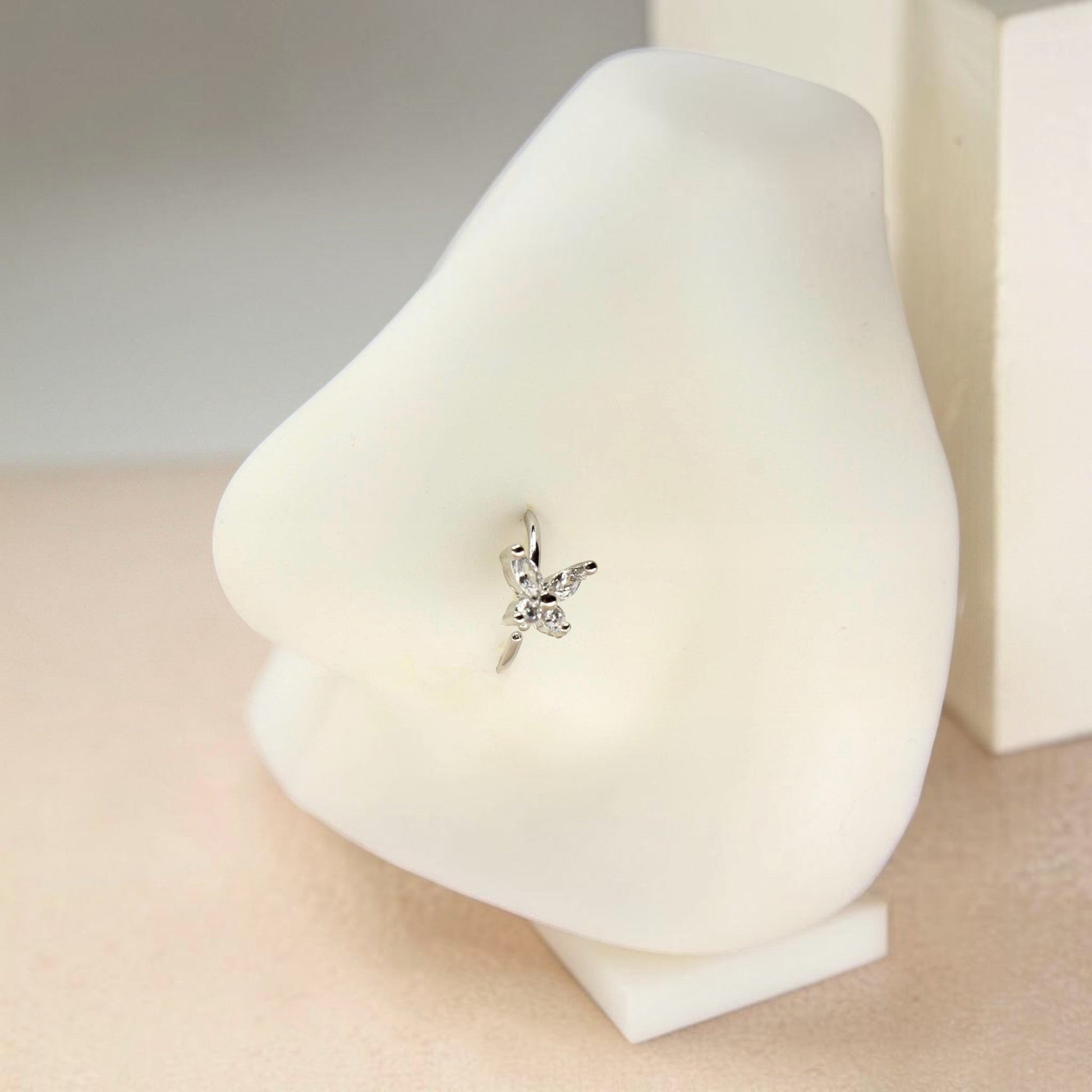 MKBodyJewelry 20g silver butterfly nose hoop with CZ stones on a white nose display model