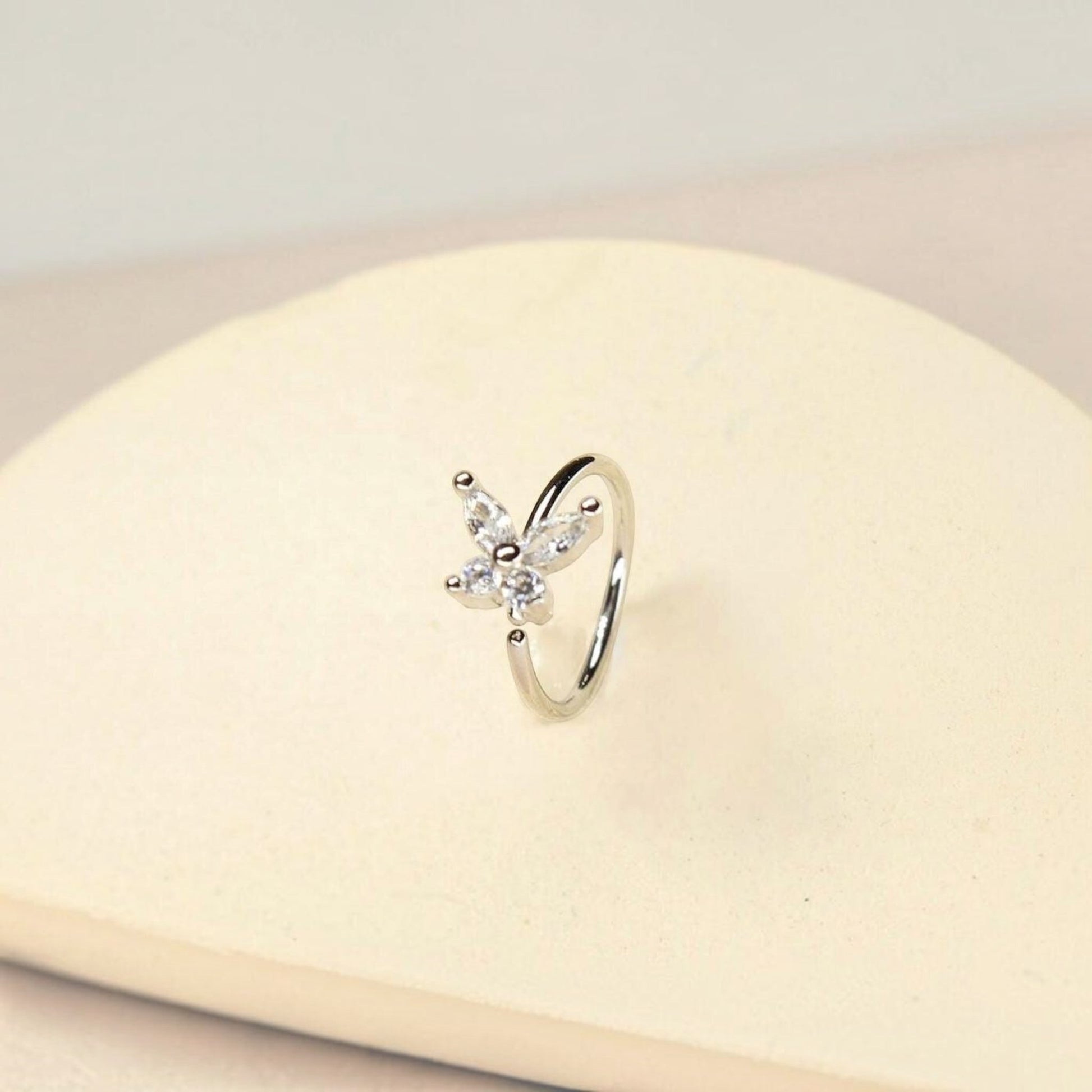 MKBodyJewelry 20g silver surgical steel nose hoop featuring a dainty butterfly charm with clear CZ stones.