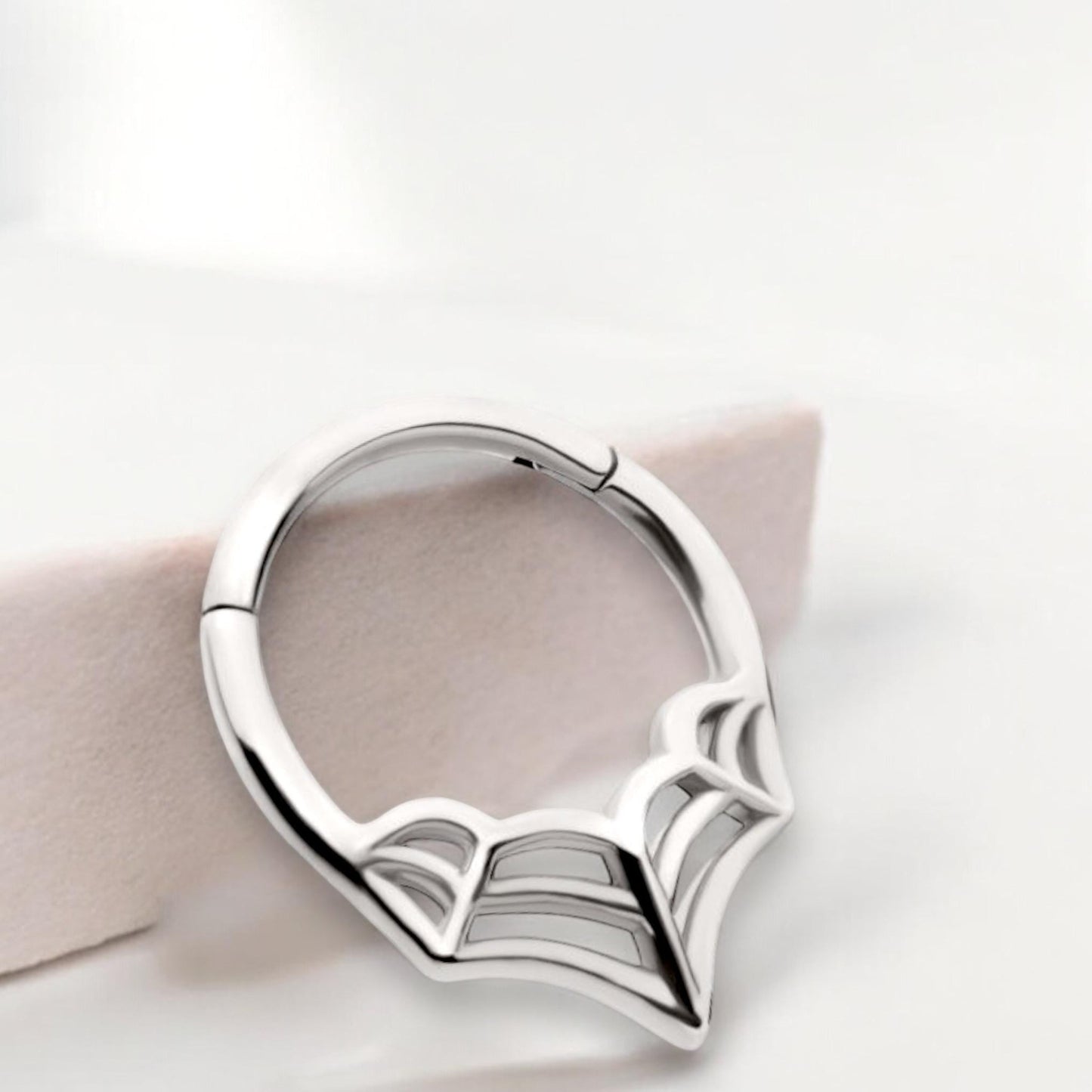 MKBodyJewelry 16G silver surgical steel septum clicker ring featuring a minimalist spider web design.