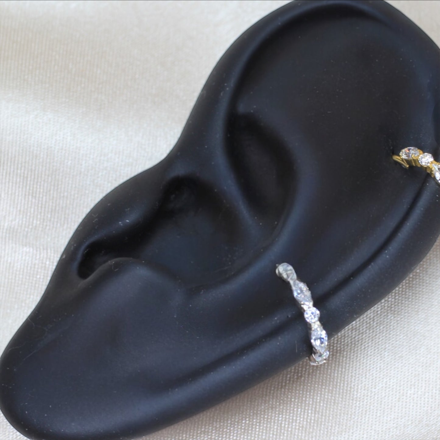 MKBodyJewelry silver titanium hinged clicker hoop ring with CZ gems displayed on a black ear model