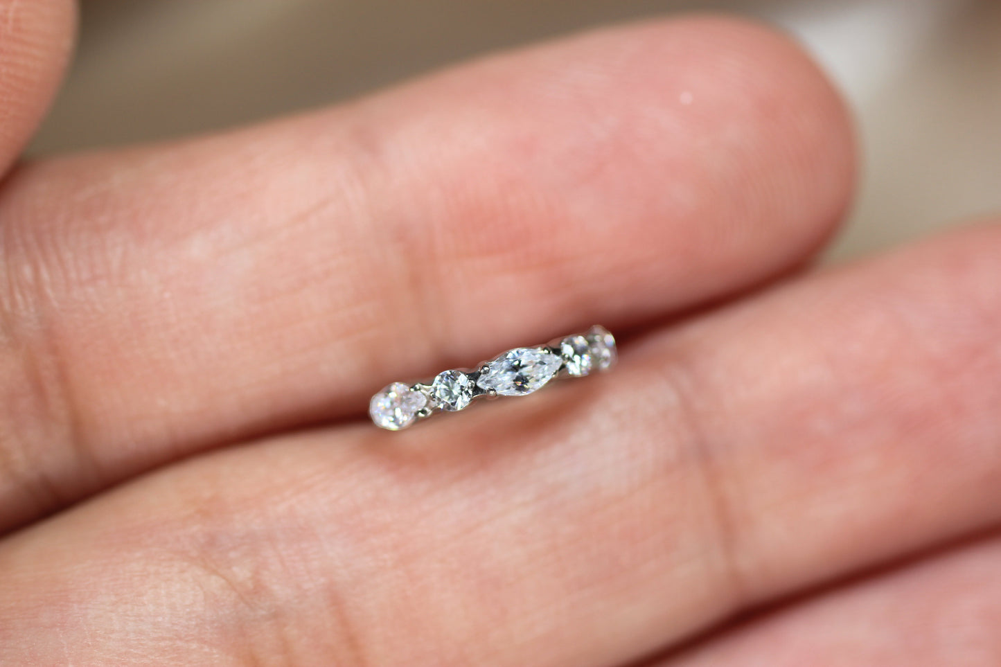 MKBodyJewelry silver titanium nose clicker ring with marquise and round CZ gems held between two fingers