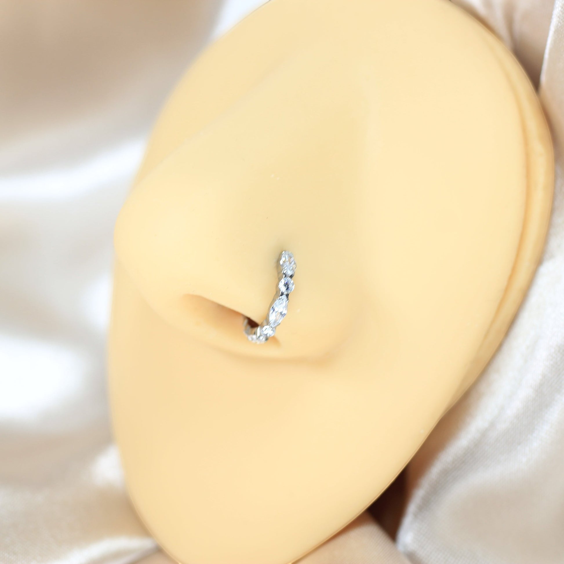 MKBodyJewelry silver titanium nose clicker ring with CZ gems on a mannequin nose for a snug, minimalist fit.