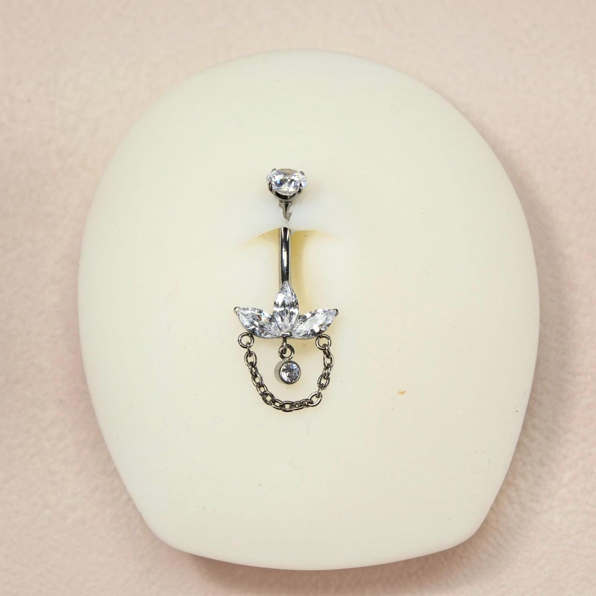 MKBodyJewelry 14G titanium belly button ring featuring a floral lotus design with marquise gems and a dangling chain.